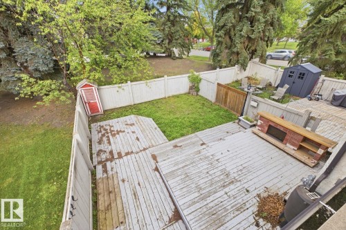 Expansive wood deck with a built-in brick feature, fenced yard, and two storage sheds - 10621 Beaumaris Road Nw, Edmonton, AB 