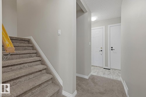 Carpeted staircase with light wood-finish handrail and decorative metal baluster - 10621 Beaumaris Road Nw, Edmonton, AB 