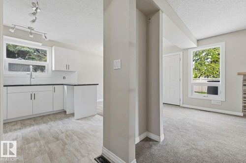 Updated kitchen with white cabinetry, dark countertops, and tile backsplash - 10621 Beaumaris Road Nw, Edmonton, AB 