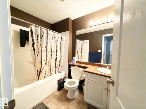 White vanity with a wood-finish countertop, undermount sink, and polished chrome faucet - #118 111 Edwards Dr Southwest, Edmonton, AB 