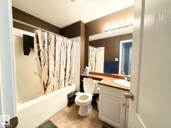 White vanity with a wood-finish countertop, undermount sink, and polished chrome faucet - 