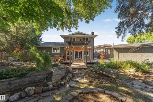 Expansive backyard featuring a stone pathway, mature landscaping, and a wooden deck with a pergola - 11208 163A Avenue Nw, Edmonton, AB 