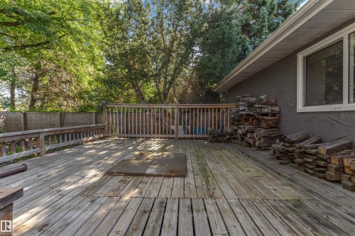 Expansive wood deck with a built-in railing system, featuring a privacy fence and abundant mature trees - 11208 163A Avenue Nw, Edmonton, AB 
