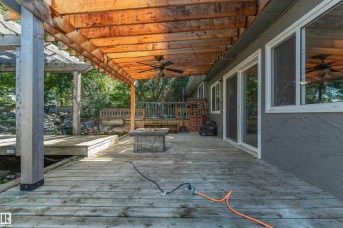 Expansive outdoor deck with a wooden pergola, ceiling fans, stone fire pit, and sliding glass doors - 11208 163A Avenue Nw, Edmonton, AB 