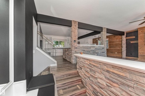 Stone-clad accent walls, wood-finish flooring, a built-in bar with a solid surface countertop, and a contemporary railing system - 11208 163A Avenue Nw, Edmonton, AB 