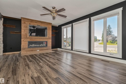 Wood-finish flooring throughout, a ceiling fan, and a fireplace with a wood-panel surround - 11208 163A Avenue Nw, Edmonton, AB 