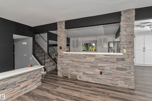 Stone veneer accents, wood-finish flooring, white countertops, built-in cabinetry, and a metal stair railing - 11208 163A Avenue Nw, Edmonton, AB 