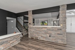 Stone veneer accents, wood-finish flooring, white countertops, built-in cabinetry, and a metal stair railing - 