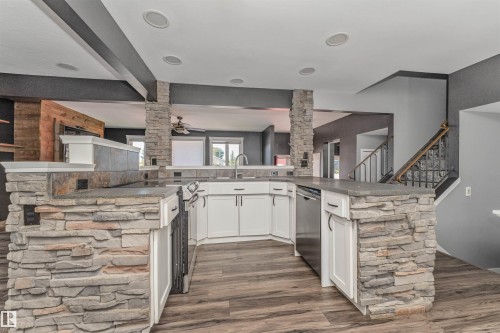 Kitchen featuring stone-clad columns, wood-finish flooring, white cabinetry, and stainless steel appliances - 11208 163A Avenue Nw, Edmonton, AB 