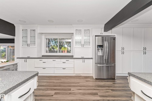 Modern kitchen featuring extensive white cabinetry, wood-finish flooring, stainless steel French door refrigerator, and speckled countertops - 11208 163A Avenue Nw, Edmonton, AB 