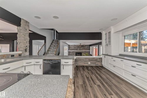 Kitchen featuring wood-finish flooring, white cabinetry, dark countertops, and a built-in dishwasher - 11208 163A Avenue Nw, Edmonton, AB 