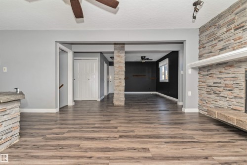 Wood-finish flooring throughout, stone-clad fireplace with mantel, ceiling fan with light fixture, and stone-clad architectural column - 11208 163A Avenue Nw, Edmonton, AB 