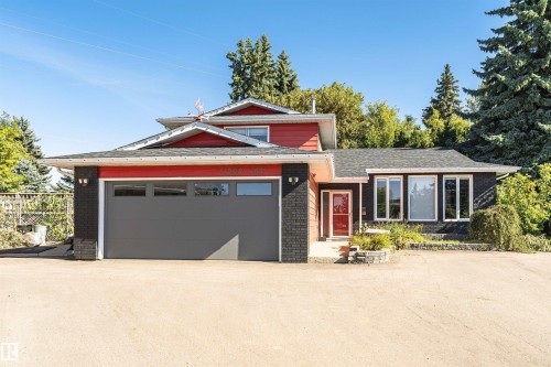Red-sided exterior with black brick accents, dark gray garage door, and multiple windows - 11208 163A Avenue Nw, Edmonton, AB 