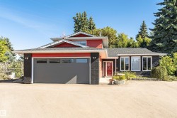 Red-sided exterior with black brick accents, dark gray garage door, and multiple windows - 