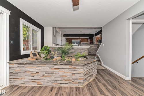 Wood-finish flooring, stone-clad interior planters, white window trim, and a staircase with a wood handrail - 11208 163A Avenue Nw, Edmonton, AB 
