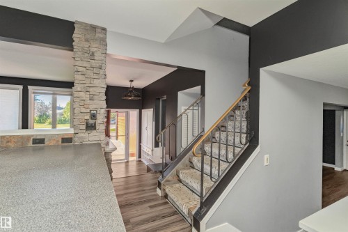 Stone accent wall with a built-in shelf, wood-finish flooring, and a staircase with a wrought iron and wood handrail - 11208 163A Avenue Nw, Edmonton, AB 