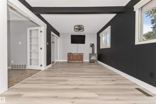 Wood-finish flooring, exposed ceiling beams, white trim, and a wood stove - 11208 163A Avenue Nw, Edmonton, AB 