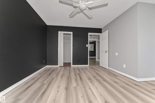 Light wood-finish flooring with white trim, a ceiling fan, and a paneled interior door - 11208 163A Avenue Nw, Edmonton, AB 
