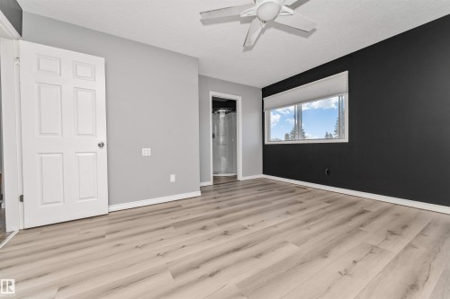 Spacious room featuring wood-finish flooring, a ceiling fan, and a large window - 11208 163A Avenue Nw, Edmonton, AB 