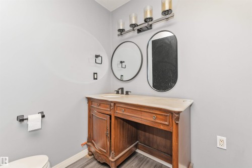 Ornate wood-finish vanity with a light-toned countertop, under-mount sink, and dark-finish faucet - 11208 163A Avenue Nw, Edmonton, AB 