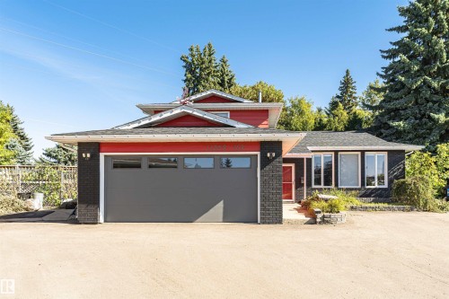 Exterior featuring red siding, black brick accents, and a gray garage door with transom windows - 11208 163A Avenue Nw, Edmonton, AB 