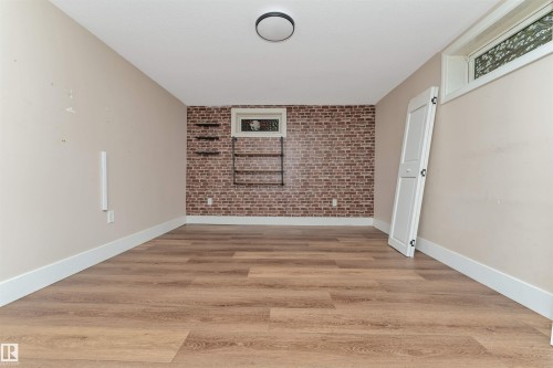 Wood-finish flooring, accent brick wall, recessed window, and flush mount ceiling light fixture - 11208 163A Avenue Nw, Edmonton, AB 