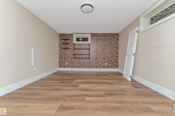 Wood-finish flooring, accent brick wall, recessed window, and flush mount ceiling light fixture - 