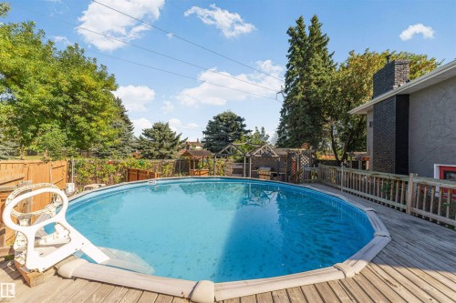 Expansive outdoor area featuring an above-ground pool, wood deck surround, privacy fencing, and mature trees - 11208 163A Avenue Nw, Edmonton, AB 
