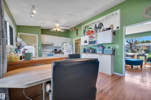 Kitchen featuring light wood-finish flooring, white cabinetry, track lighting, and a ceiling fan - 8812 135A Avenue Nw, Edmonton, AB 