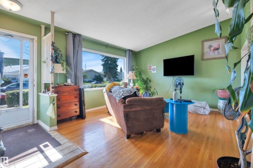 Hardwood-style flooring throughout, expansive window, wall-mounted television, and a full-light entry door - 8812 135A Avenue Nw, Edmonton, AB 