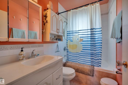 Bathroom featuring a vanity with an integrated sink, wall-mounted mirrored cabinet, and built-in storage cabinets - 8812 135A Avenue Nw, Edmonton, AB 