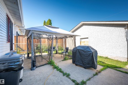 Paved patio area with a privacy fence and a white stucco exterior wall - 8812 135A Avenue Nw, Edmonton, AB 