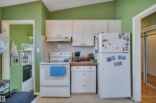 Kitchen featuring white cabinetry, a white electric range, and a white refrigerator - 8812 135A Avenue Nw, Edmonton, AB 