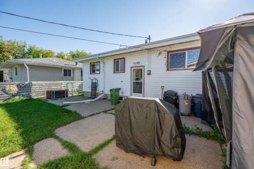 White vinyl siding exterior with two windows featuring brown trim - 8812 135A Avenue Nw, Edmonton, AB 