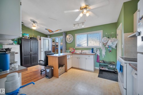 Kitchen featuring a double window, ceiling fans, and a combination of tile and wood-finish flooring - 8812 135A Avenue Nw, Edmonton, AB 