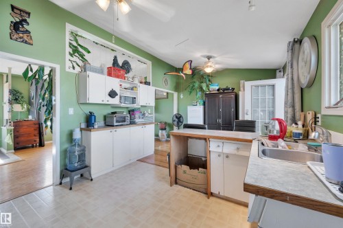 Kitchen featuring wood-finish flooring, white cabinetry, a built-in sink, and a glass-paneled exterior door - 8812 135A Avenue Nw, Edmonton, AB 