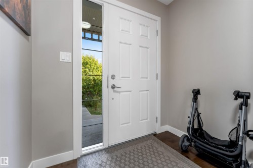 Entryway featuring a white paneled door, a full-length sidelight, dark wood-finish flooring, and light gray wall paint - 136 55 Street Sw, Edmonton, AB 