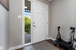 Entryway featuring a white paneled door, a full-length sidelight, dark wood-finish flooring, and light gray wall paint - 