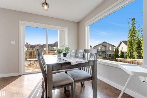Wood-finish flooring, sliding glass door, large picture window, and a modern ceiling light fixture - 136 55 Street Sw, Edmonton, AB 