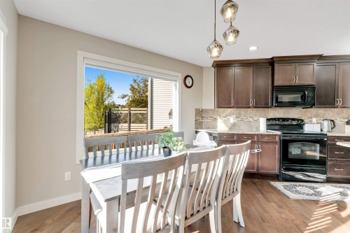 Kitchen dining area featuring wood-finish flooring, dark wood cabinetry, a tiled backsplash, and recessed lighting - 136 55 Street Sw, Edmonton, AB 