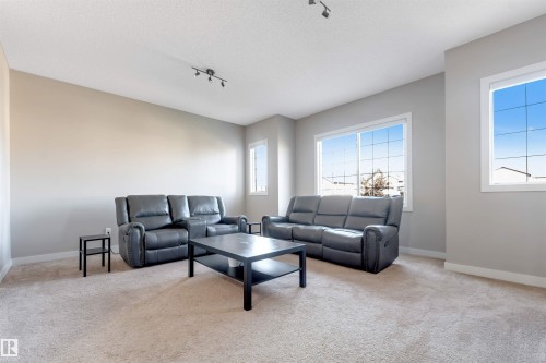 Carpeted room with multiple large windows, track lighting, and neutral wall tones - 136 55 Street Sw, Edmonton, AB 