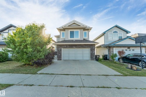 Two-story property featuring light gray siding, dark gray stone detailing, and an attached two-car garage - 136 55 Street Sw, Edmonton, AB 