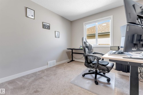 Neutral wall paint, window with white trim, light-toned carpeting, and a textured ceiling - 136 55 Street Sw, Edmonton, AB 
