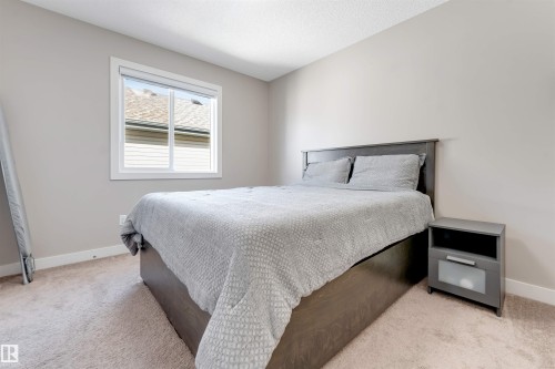 Neutral paint palette, carpeted flooring, window with white trim, and a built-in nightstand - 136 55 Street Sw, Edmonton, AB 