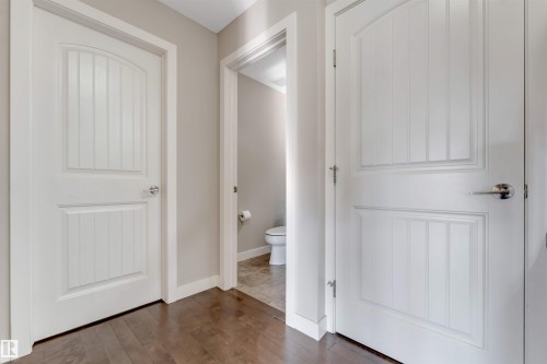 Hardwood-style flooring throughout, complemented by white interior doors featuring panel detailing and chrome hardware - 136 55 Street Sw, Edmonton, AB 