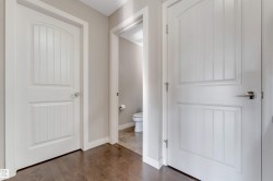 Hardwood-style flooring throughout, complemented by white interior doors featuring panel detailing and chrome hardware - 