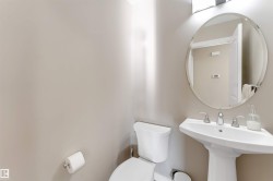 Pedestal sink with chrome fixtures and an oval, frameless mirror - 