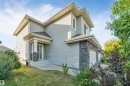 Two-story exterior with light gray siding, stone accents, a covered entry, and an integrated garage - 136 55 Street Sw, Edmonton, AB 