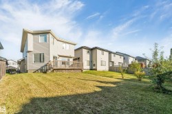 Expansive rear yard with a wooden deck, mature trees, and landscaping - 