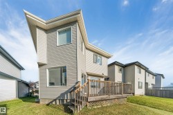 Exterior featuring siding, multiple windows, a wooden deck with railing, and a sloped lawn - 